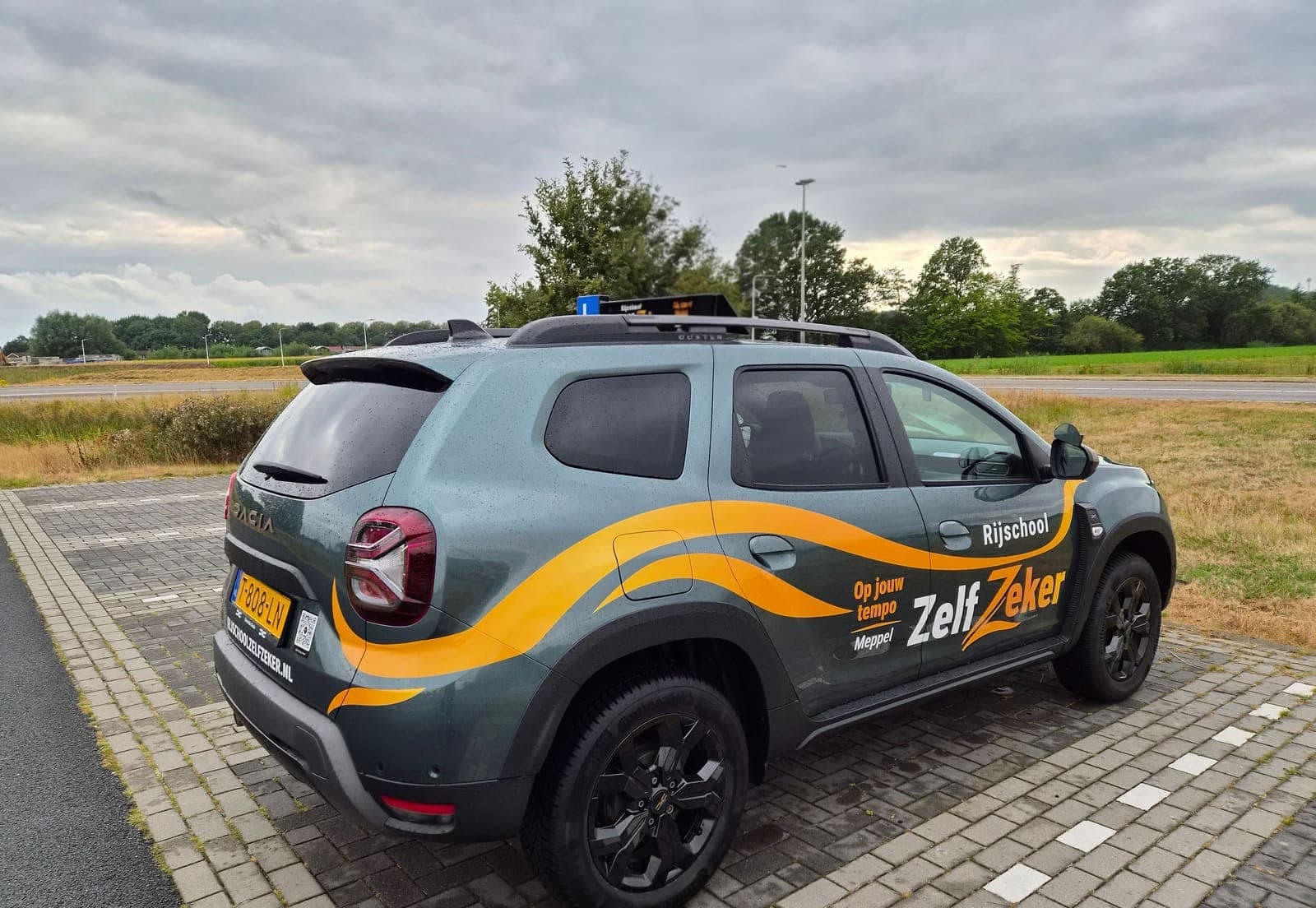 De ZelfZeker-lesauto schuin van achteren